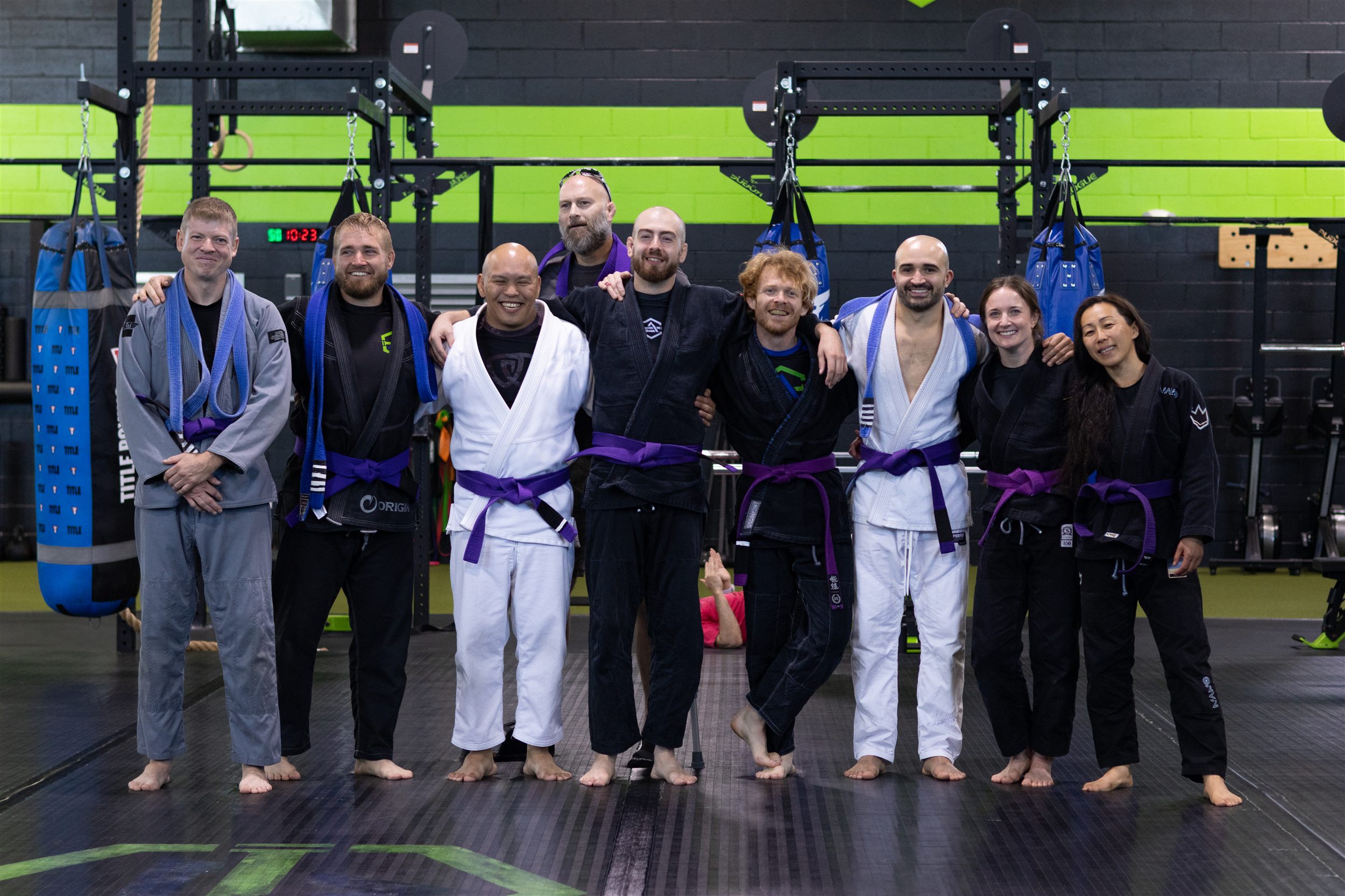 Evolution Athletix Brazilian Jiu Jitsu purple belts lined up after the promotion ceremony, including coaches Alyssa Taylor and Dan Lenzi